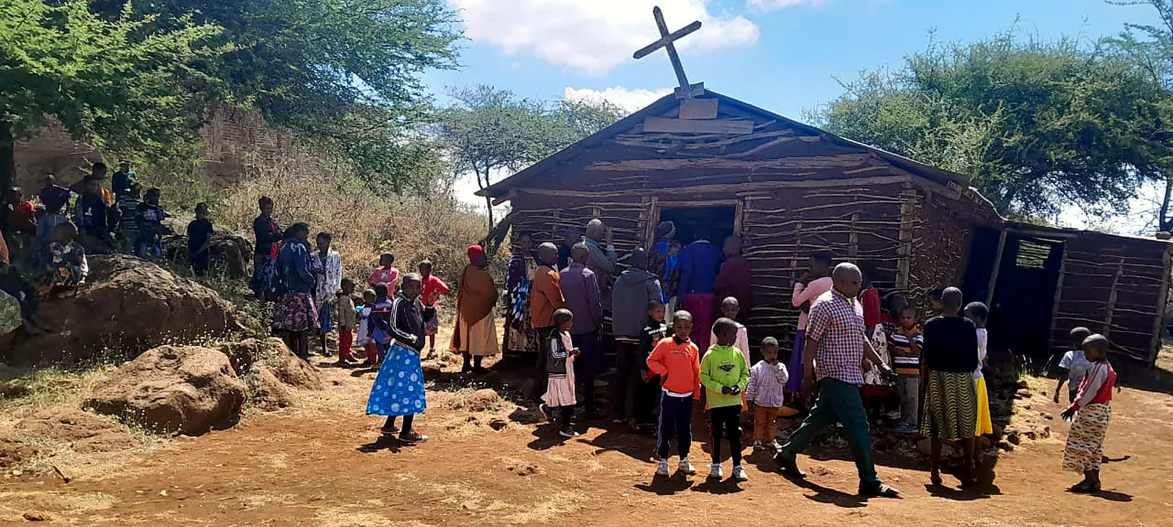 The church holds a fraction of the people who come, so the rest gather in the open ground outside it.