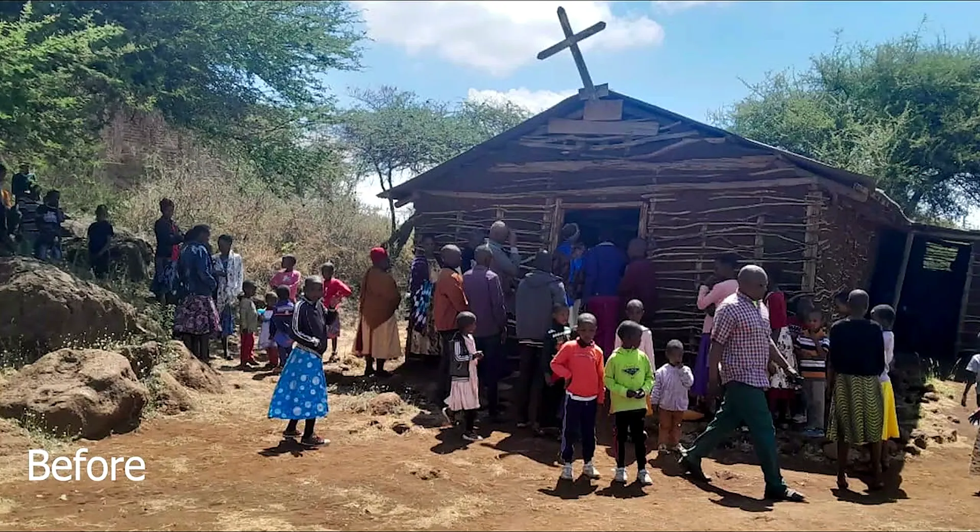 A frame from the film: the whole village gathered outside the small timber church at Upper Kitete, a wooden cross on its roof.