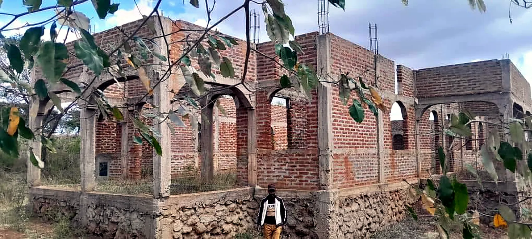 The new church on its cut stone foundation. The figure standing at the wall gives the scale of the building.